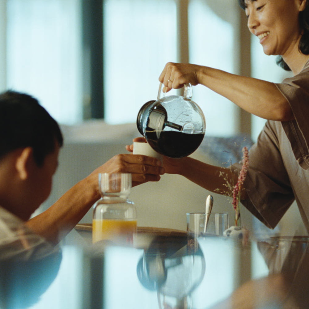 woman pouring coffee to a coffee mug using the glass carafe to the aarke coffee maker.