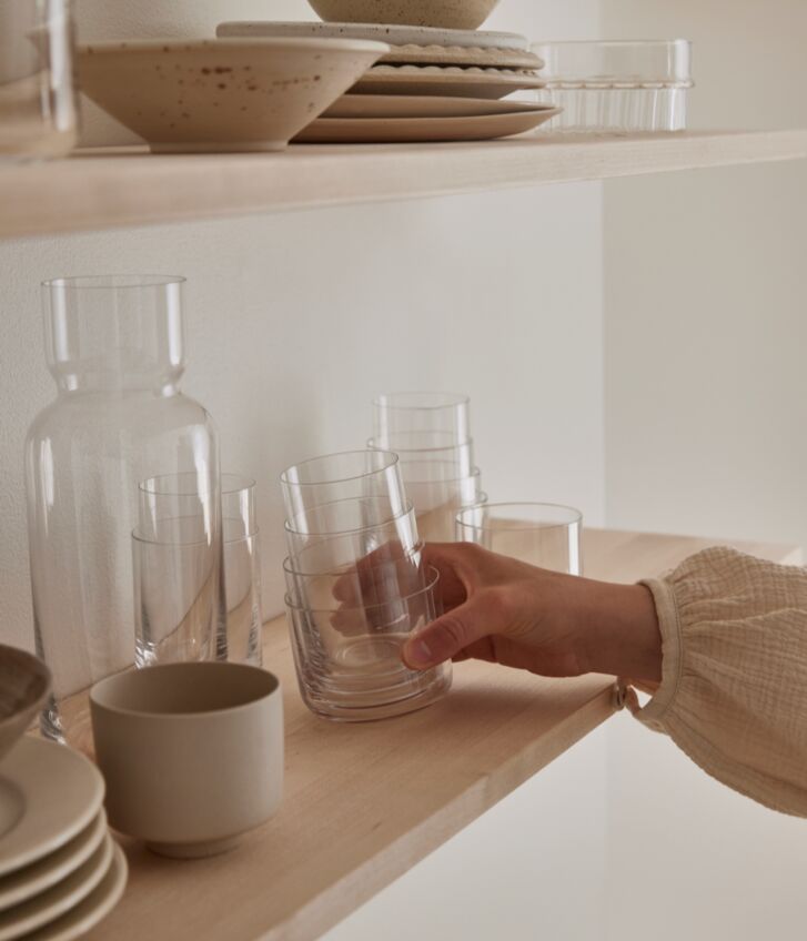 Someone is placing the stacked Nesting Glasses onot a shelf.