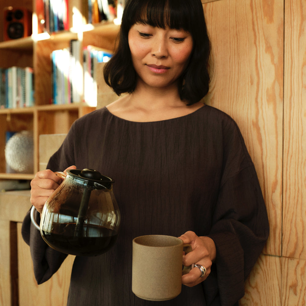 woman holding the glass carafe with freshly brewed coffee from the aarke coffee maker